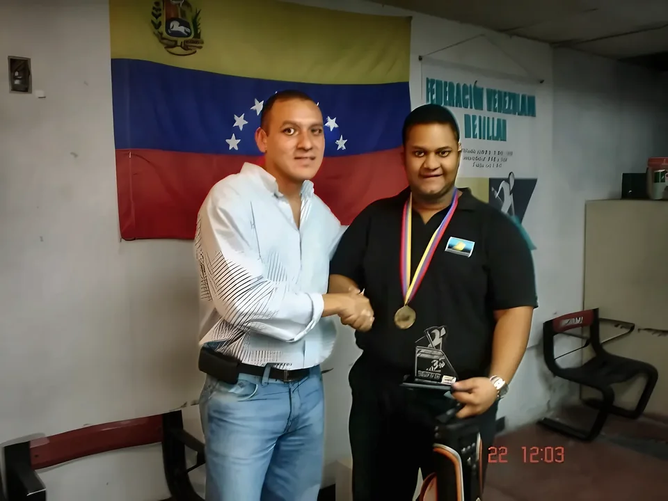 Medalla y trofeo ante la bandera de Venezuela y el pendón de la Federación.